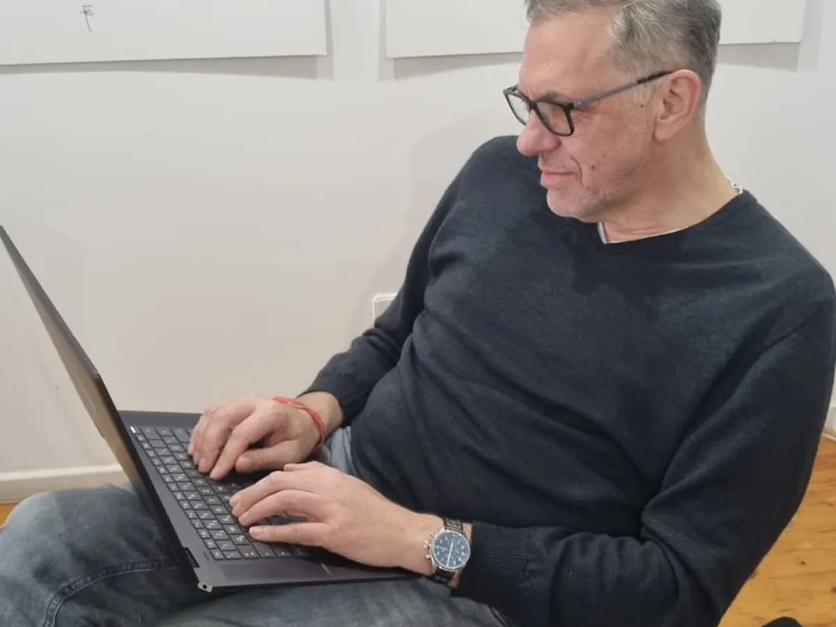 Ein Mann tippt auf seinem Laptop, neben ihm liegt ein Notizbuch