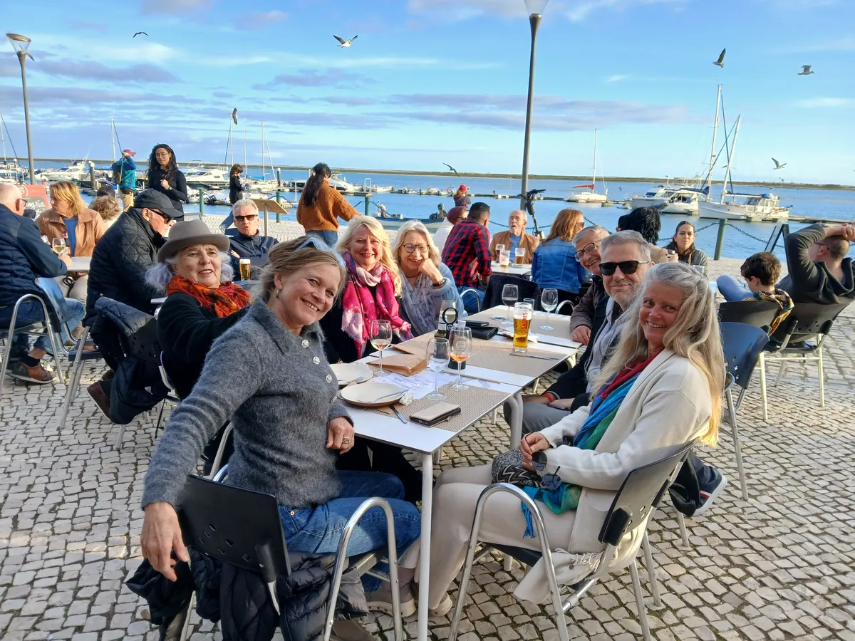 Workshop-Gruppe an einem Tisch am Hafen, die Teilnehmenden lächeln in die Kamera